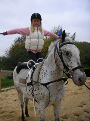 Eine Person kniet auf einem Pferd und streckt die Arme aus